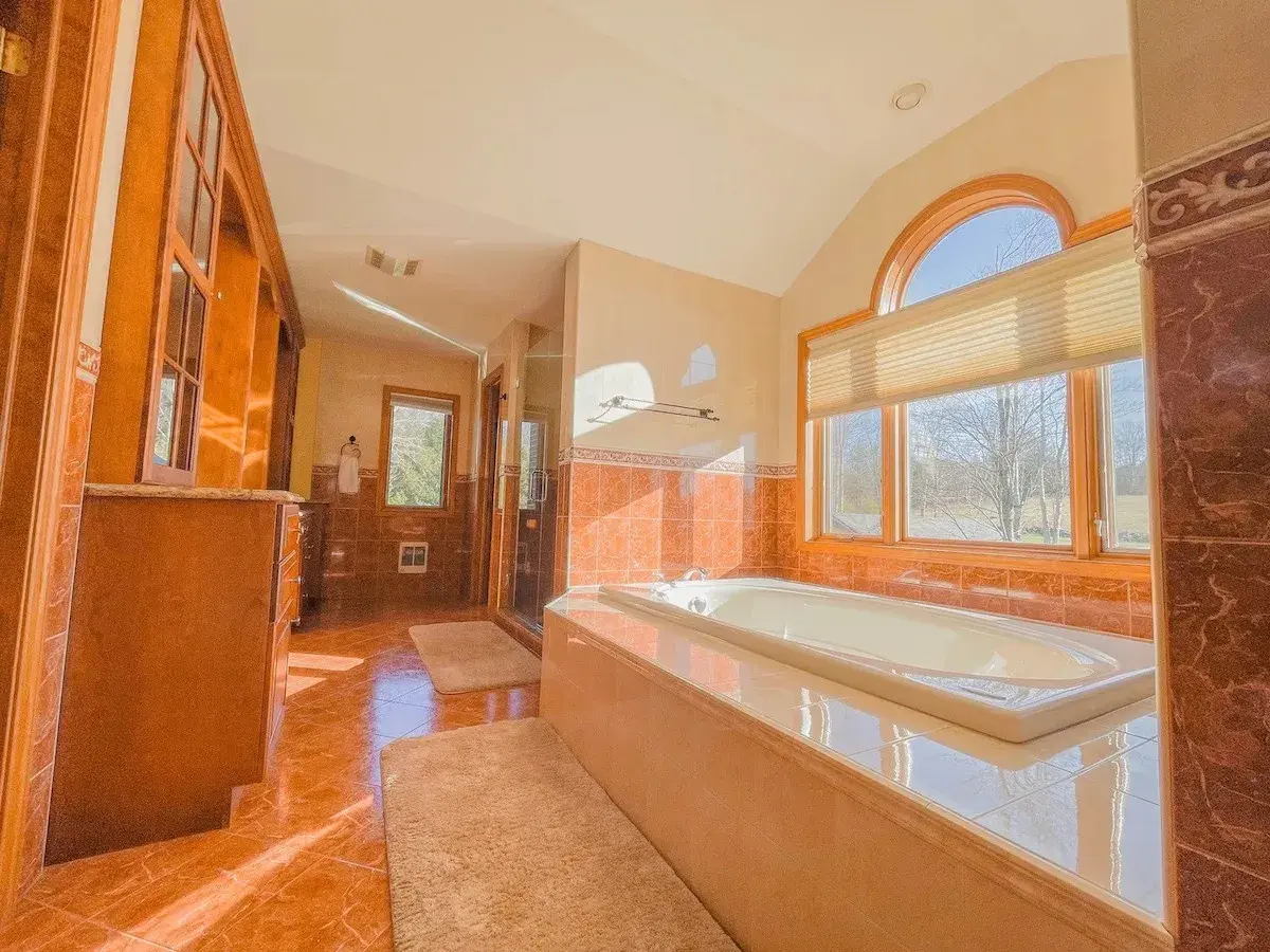 A bathroom with a jetted tub under an arched window