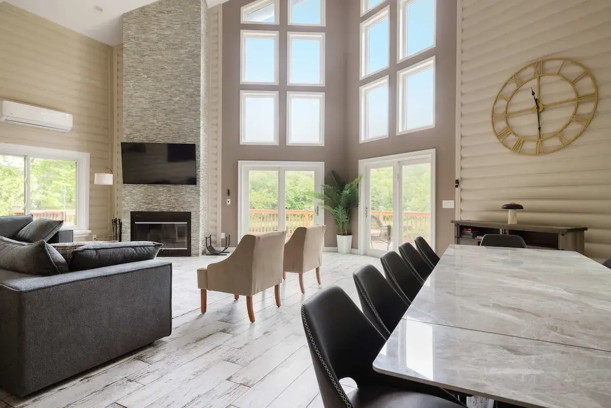 The great room at The Lake House: window walls, a stone fireplace and a long dining table
