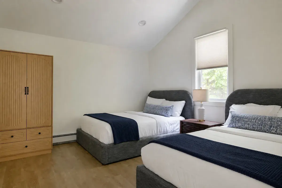 A bedroom with two beds and navy throws